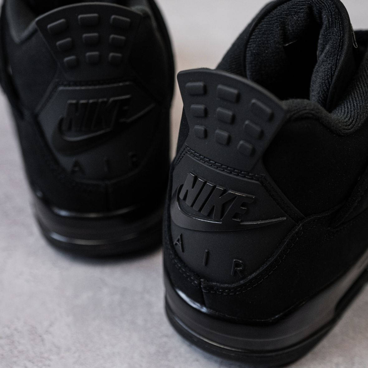 Air Jordan 4 Black Cat 2025 heel shot from high angle flatlay on marble floor