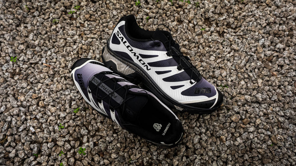 Image via The Sole Supplier Footpatrol x Salomon XT-4 Black Vanilla Ice against gravel stone urbanscape background