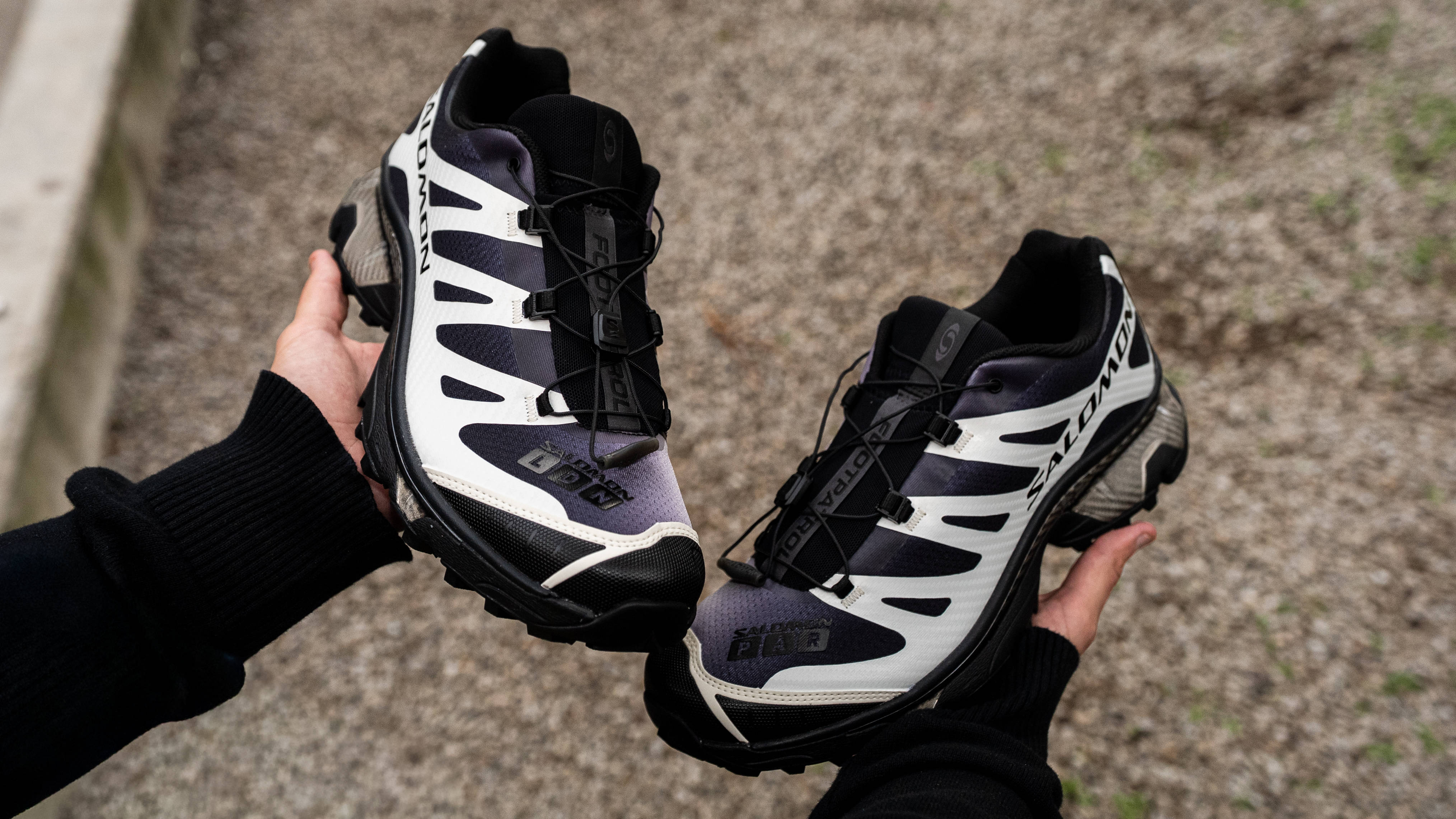 Footpatrol x Salomon XT-4 Black Vanilla Ice in-hand against stone background