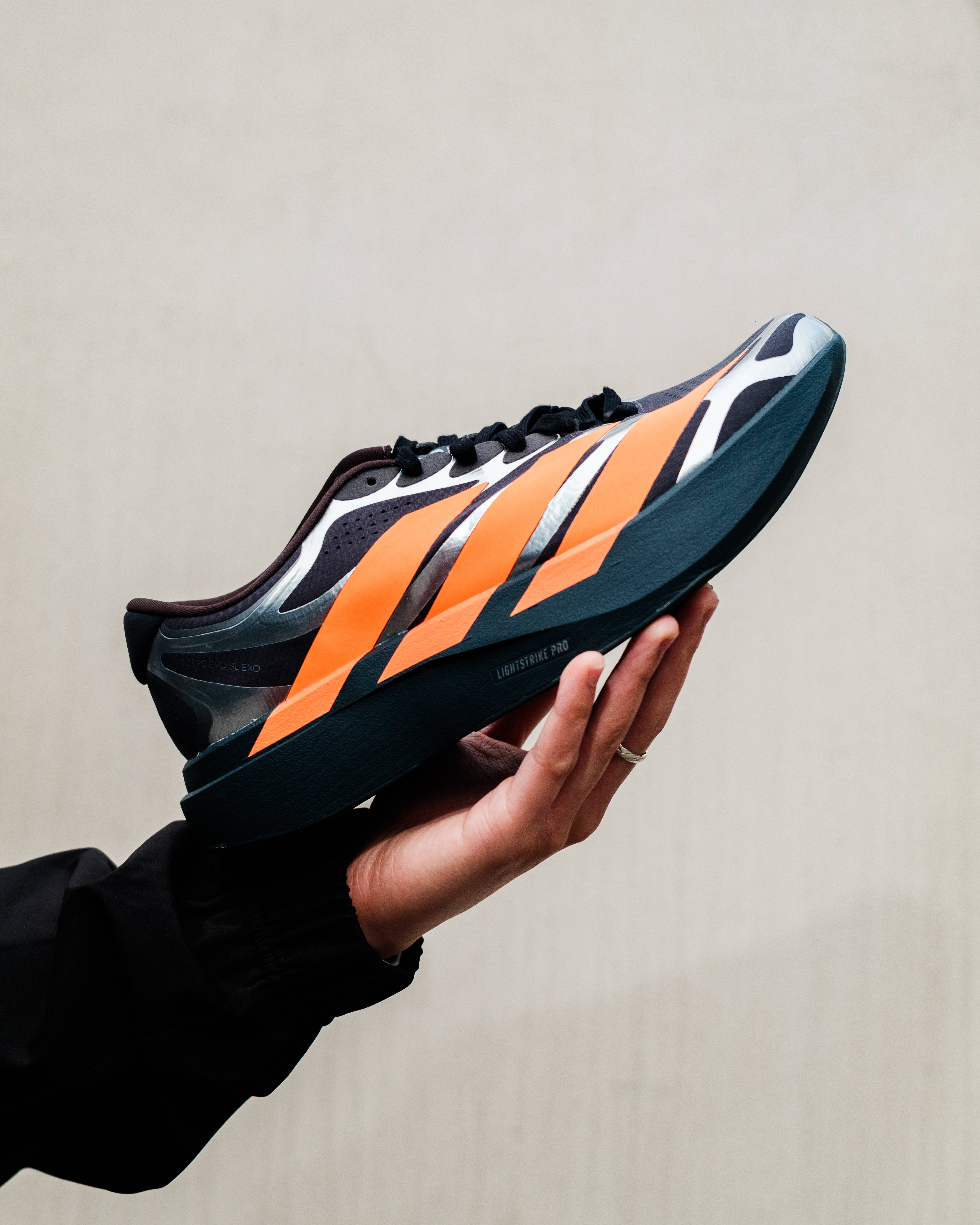 adidas evo sl exo carbon lucid orange side profile in hand beige backdrop