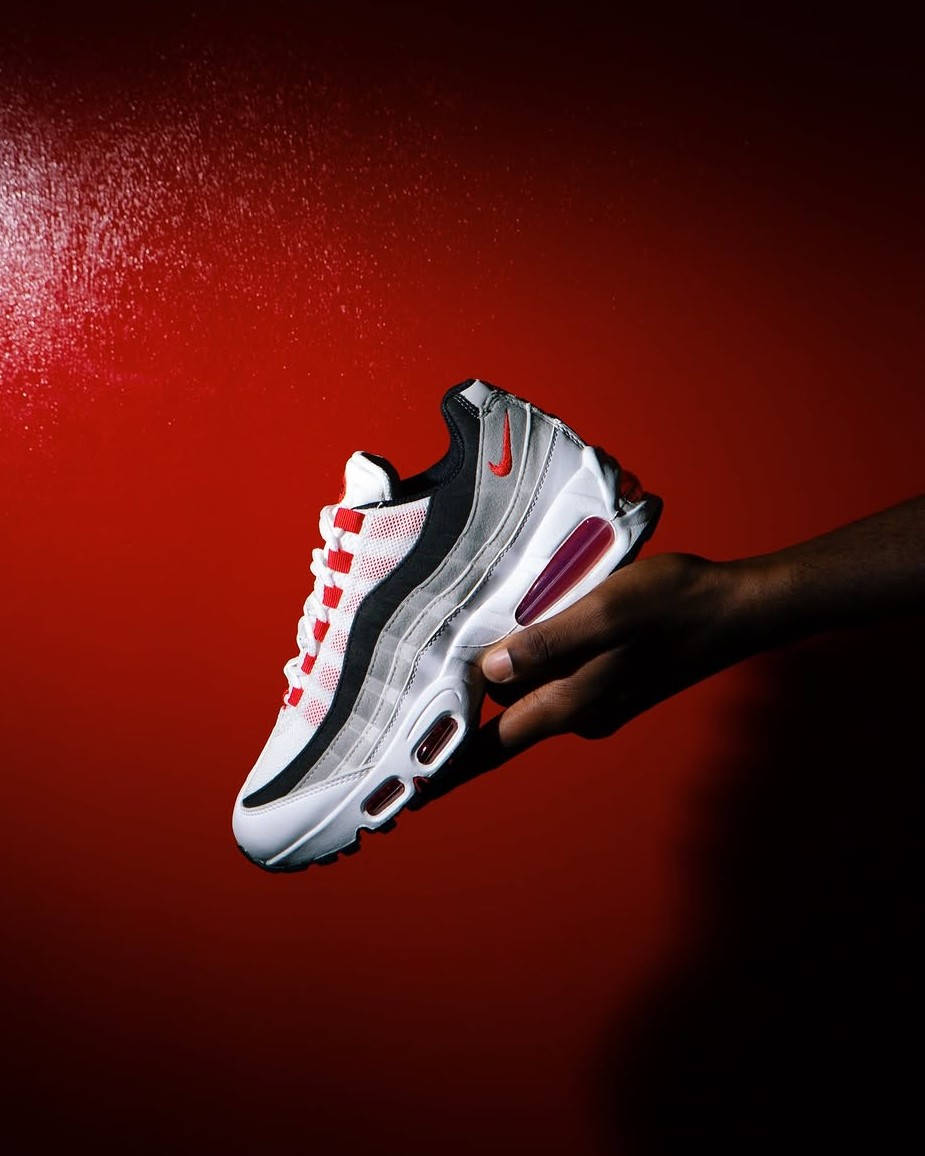 comed red air max 95 in hand against red wall backdrop