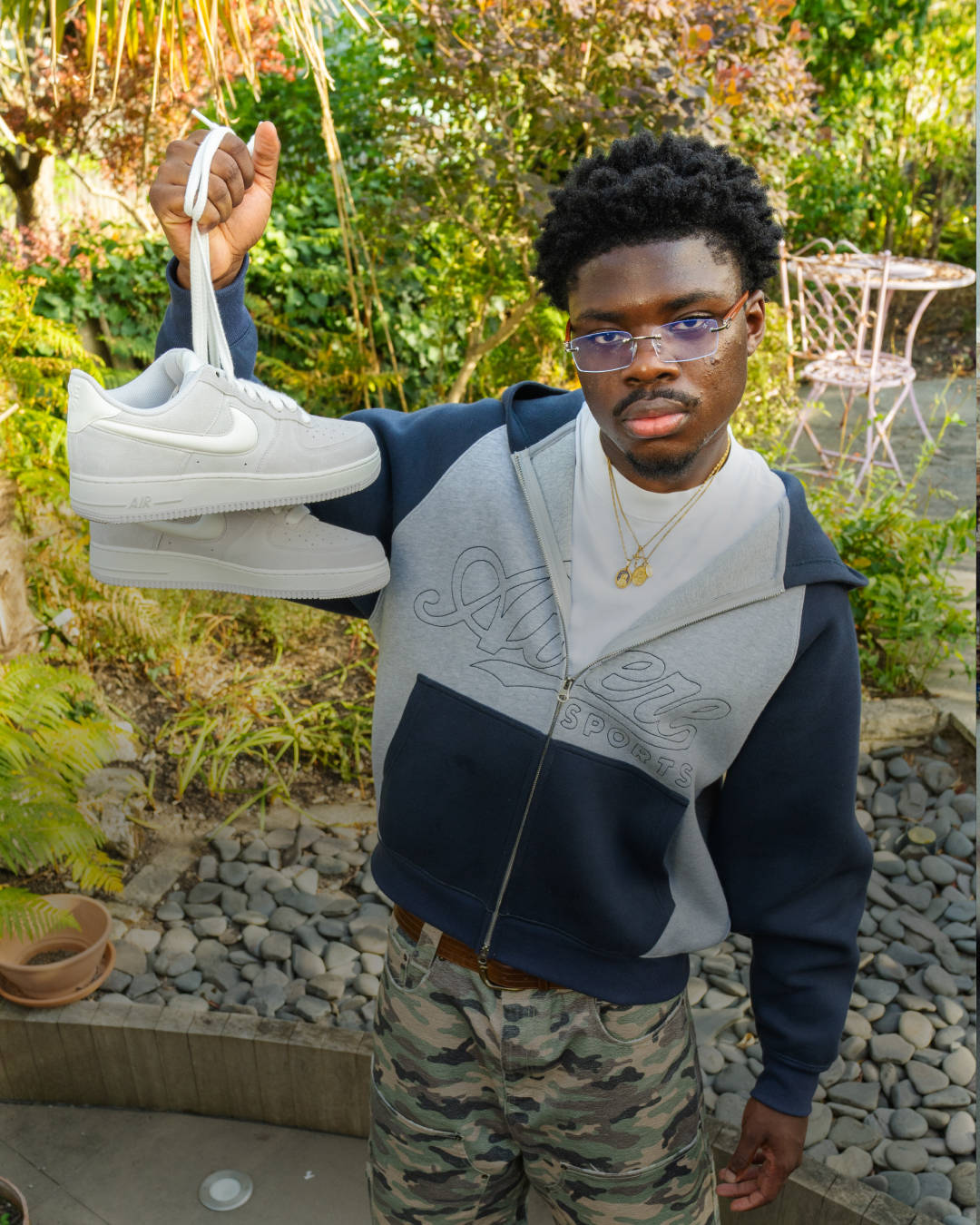 nike air force 1 editorial model holding up shoe by the laces surrounded by nature backdrop