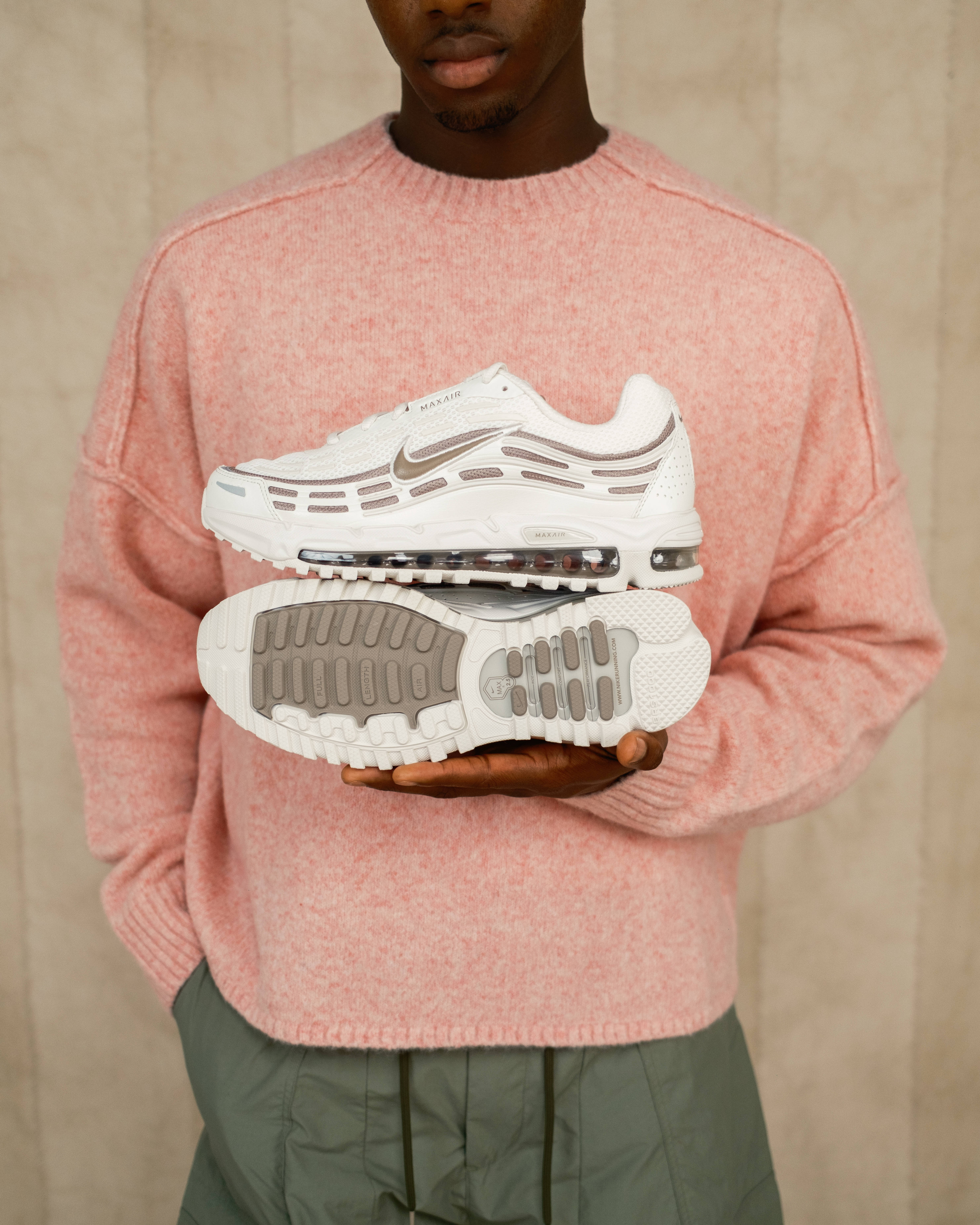 nike air max tl 2.5 phantom pair in hand against pink jumper editorial