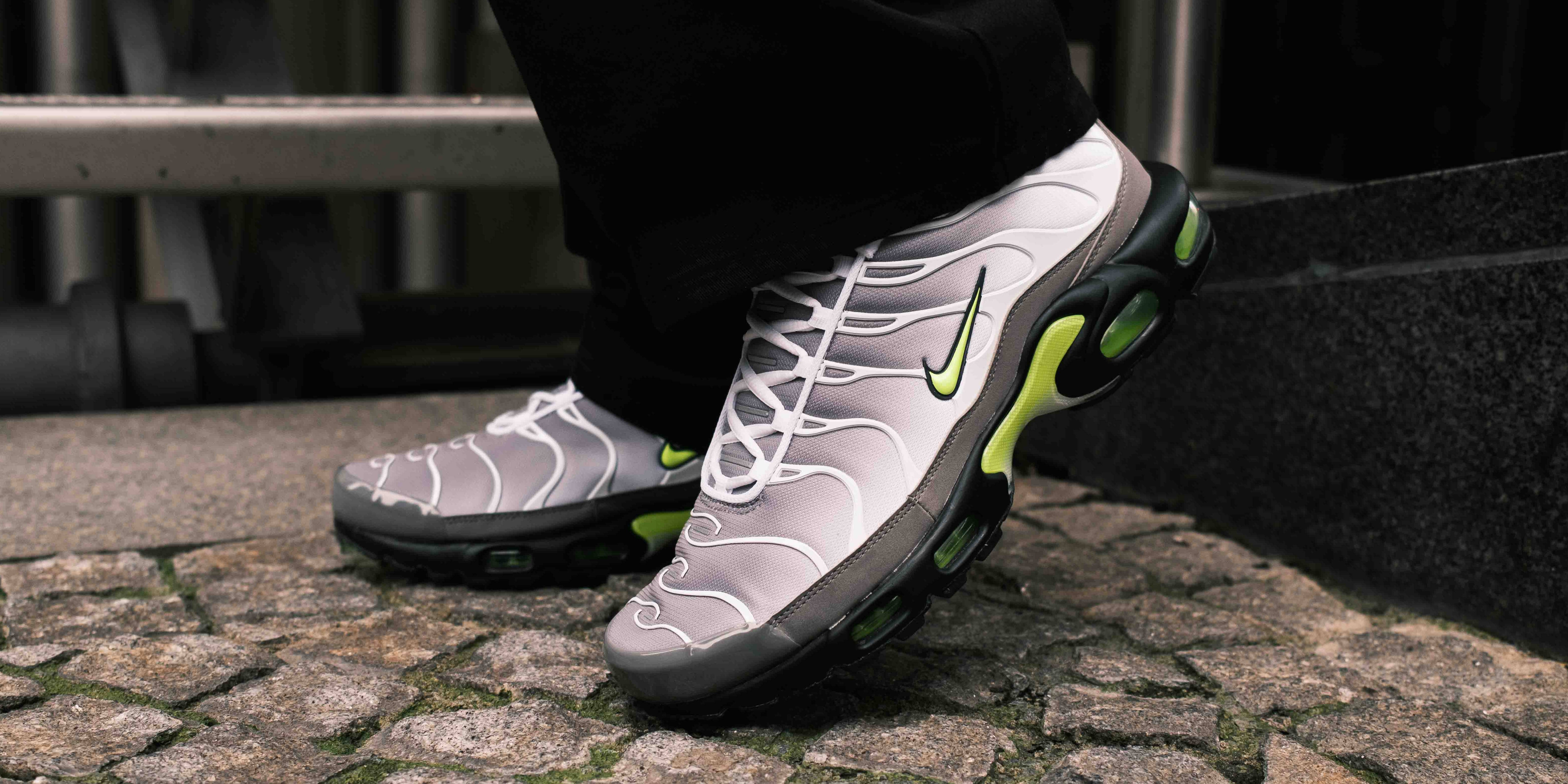 neon tn nike air max plus on feet street backdrop