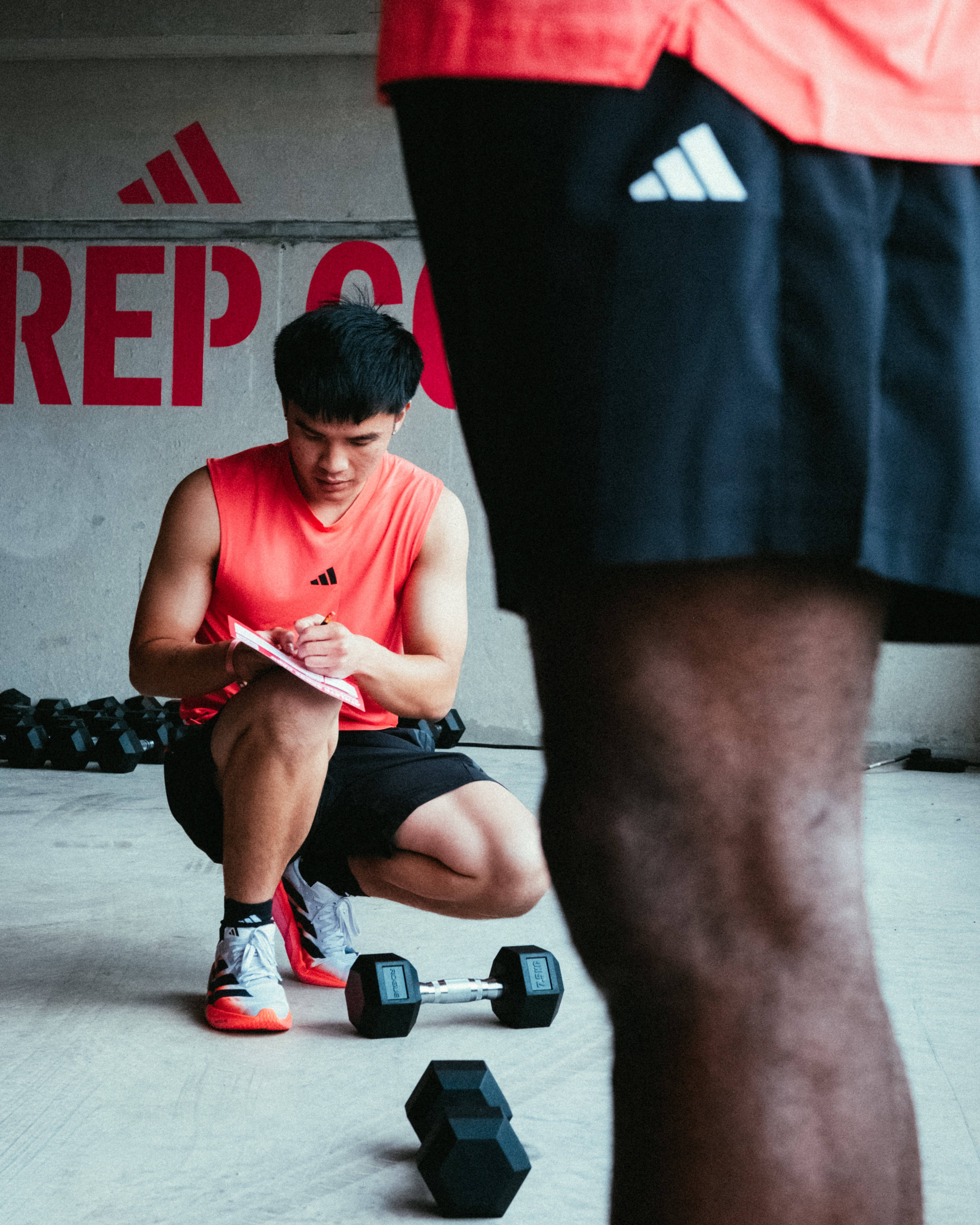 male athlete hybrid crouched down taking notes during exercise adidas activation