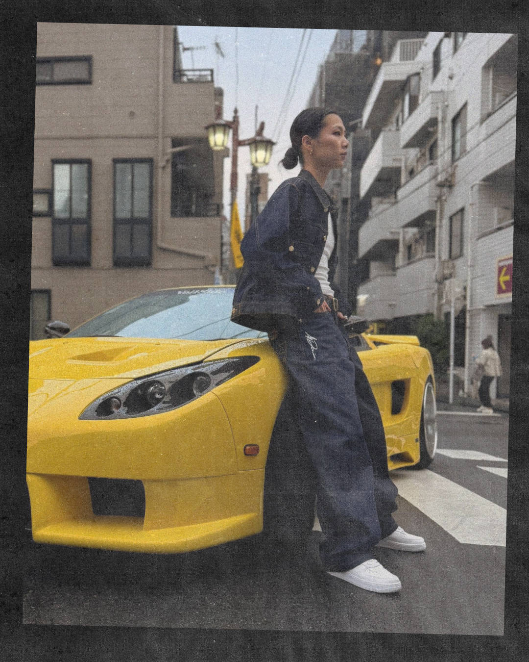 beams x a1 denim collaboration female model in two piece denim suit perched next to yellow supercar in shibuya wearing triple white air force 1s