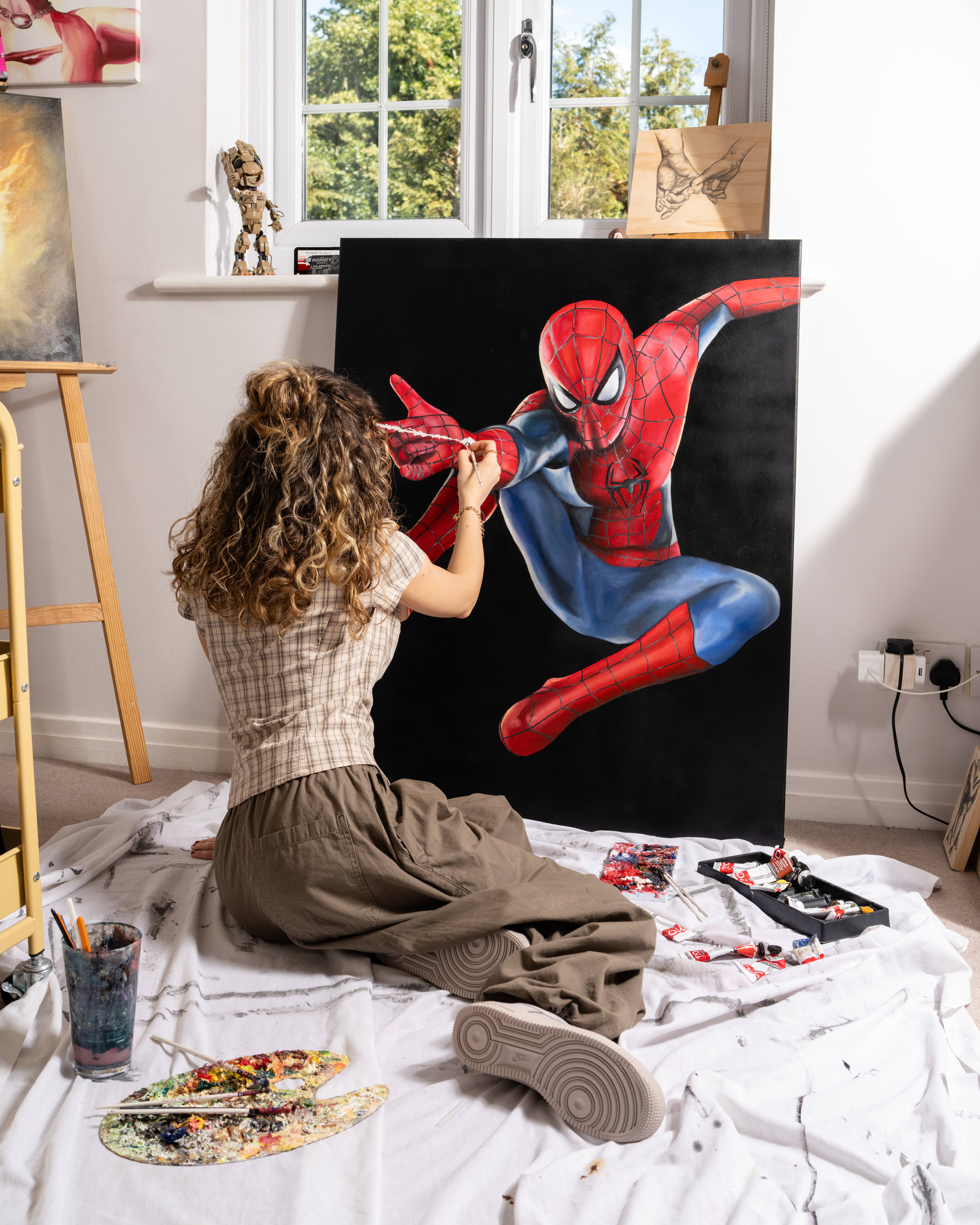 air force 1 worn by emilia poyiadgi while she paints her spiderman portrait on canvas
