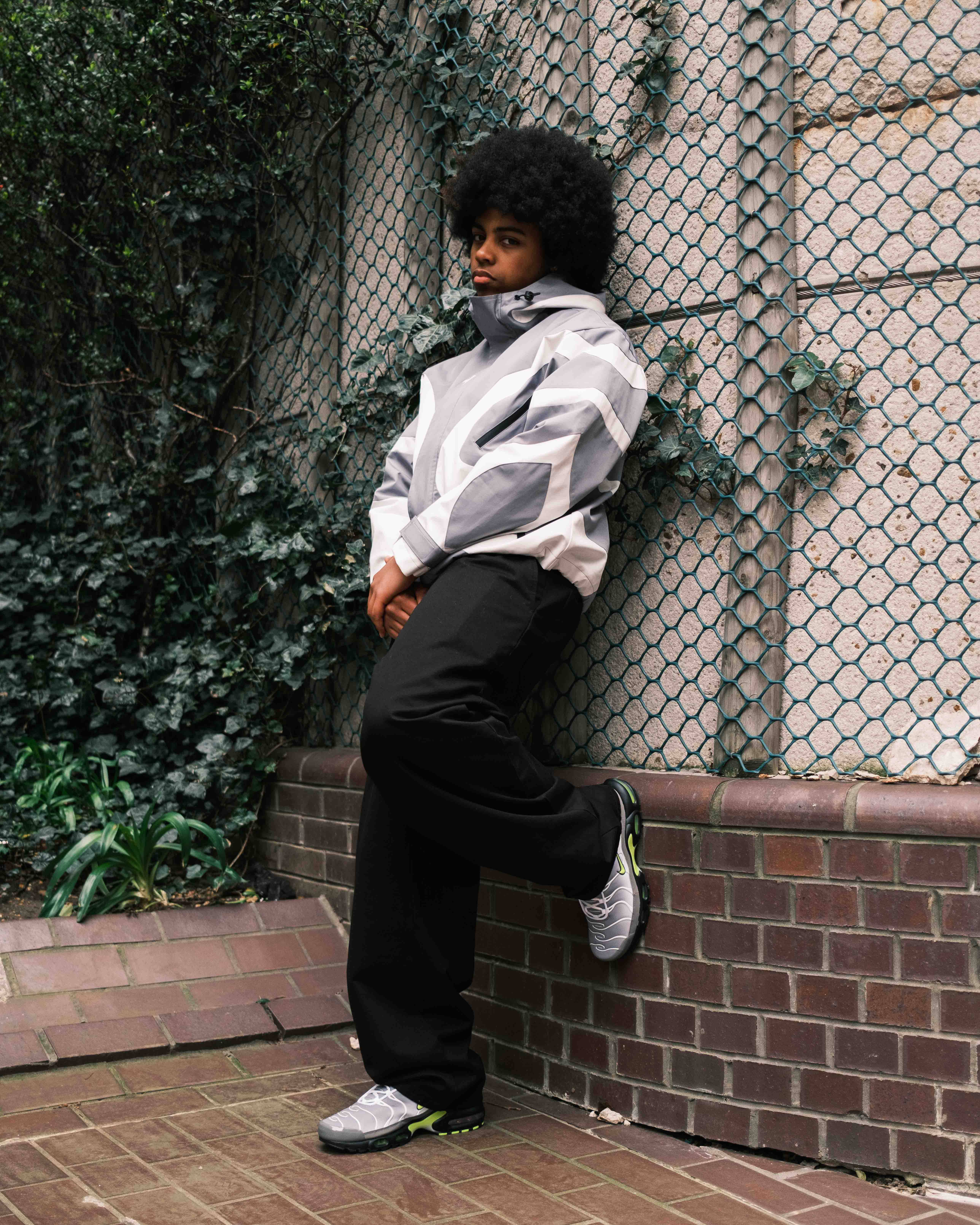 model wearing neon tns leaning up against wall