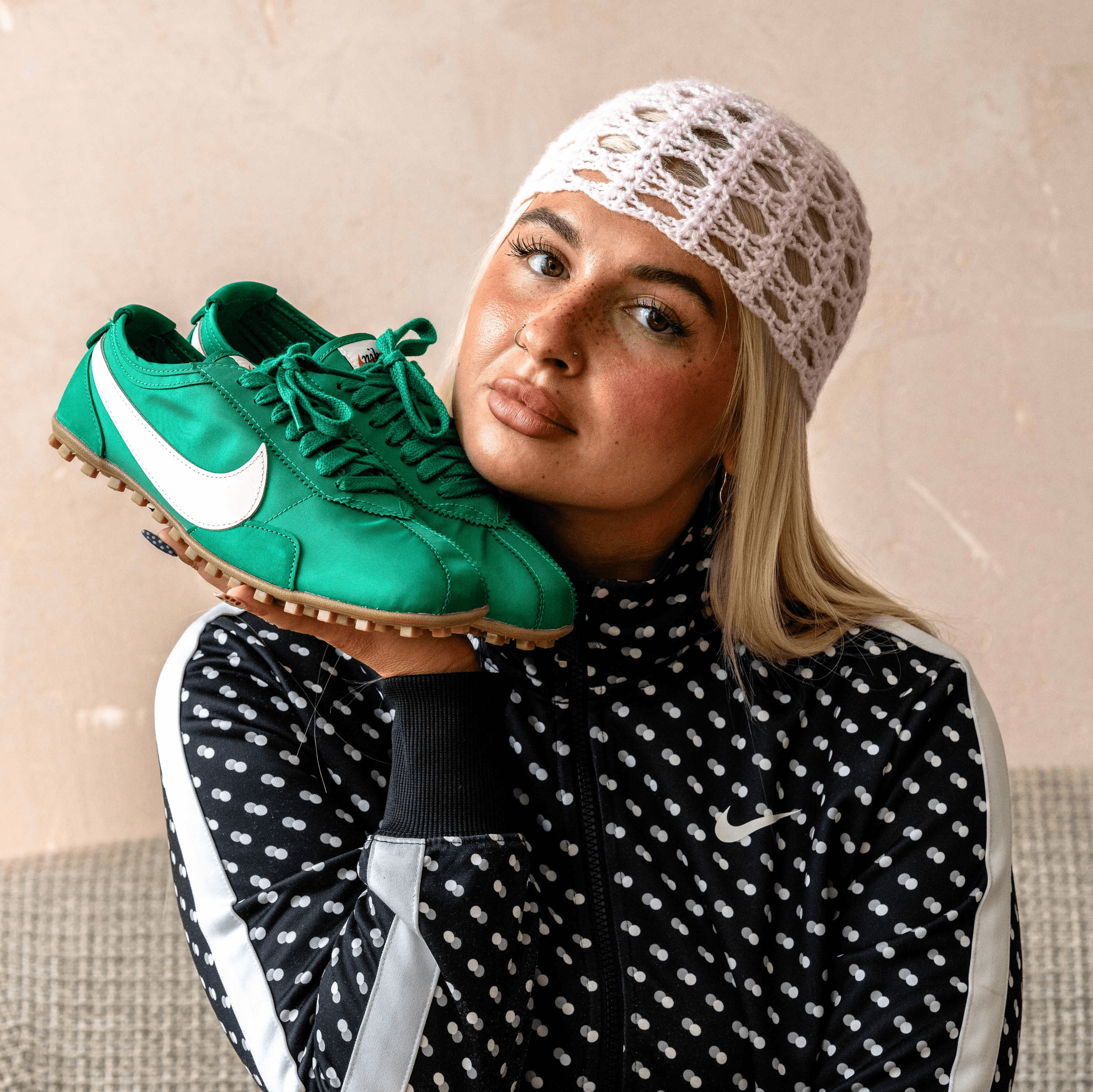 Nike Moon shoe green pair held up in hand to model's face blonde hair polka dot nike jacket worn