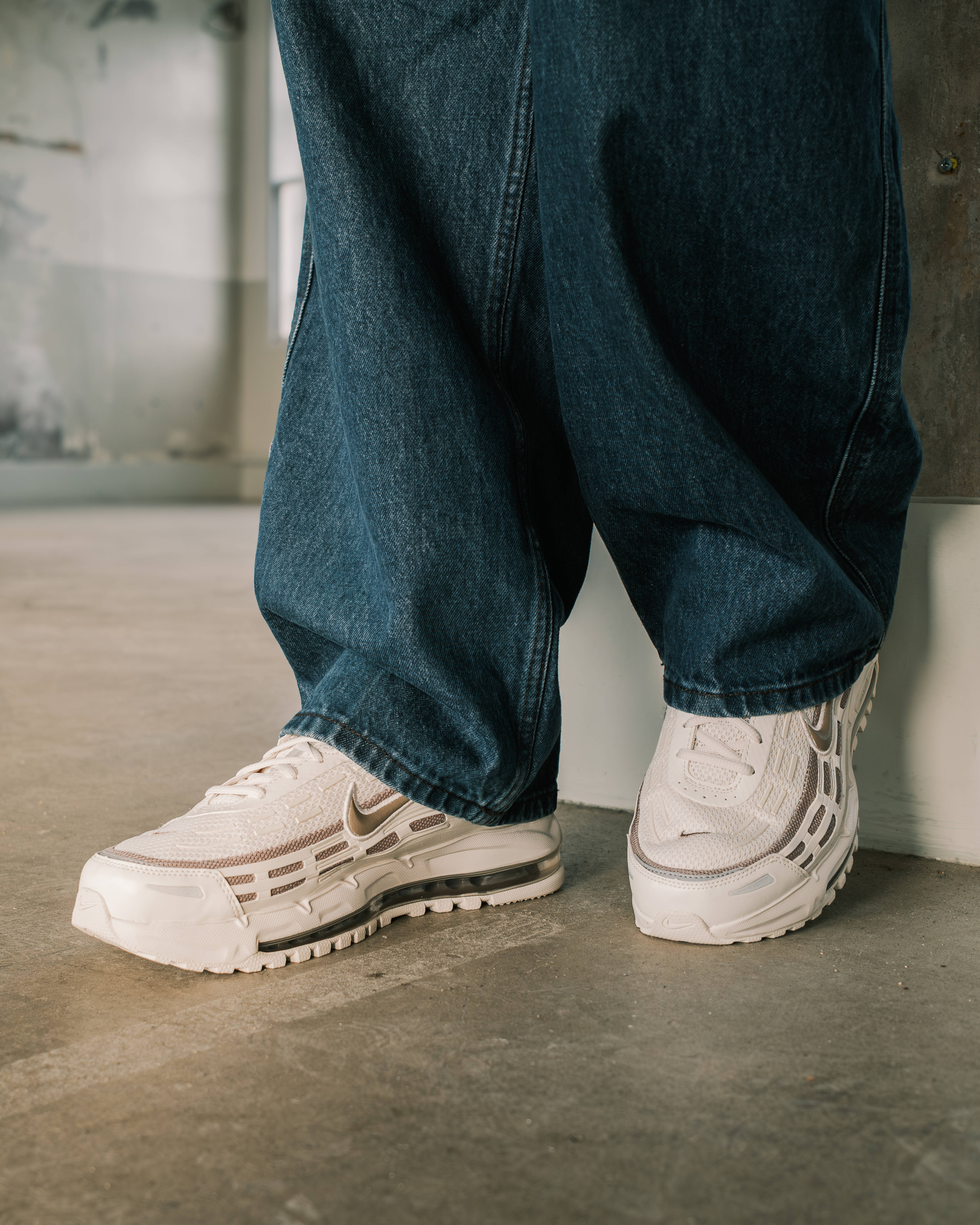 nike air max TL 2.5 styled with dark denim against rustic backdrop editorial
