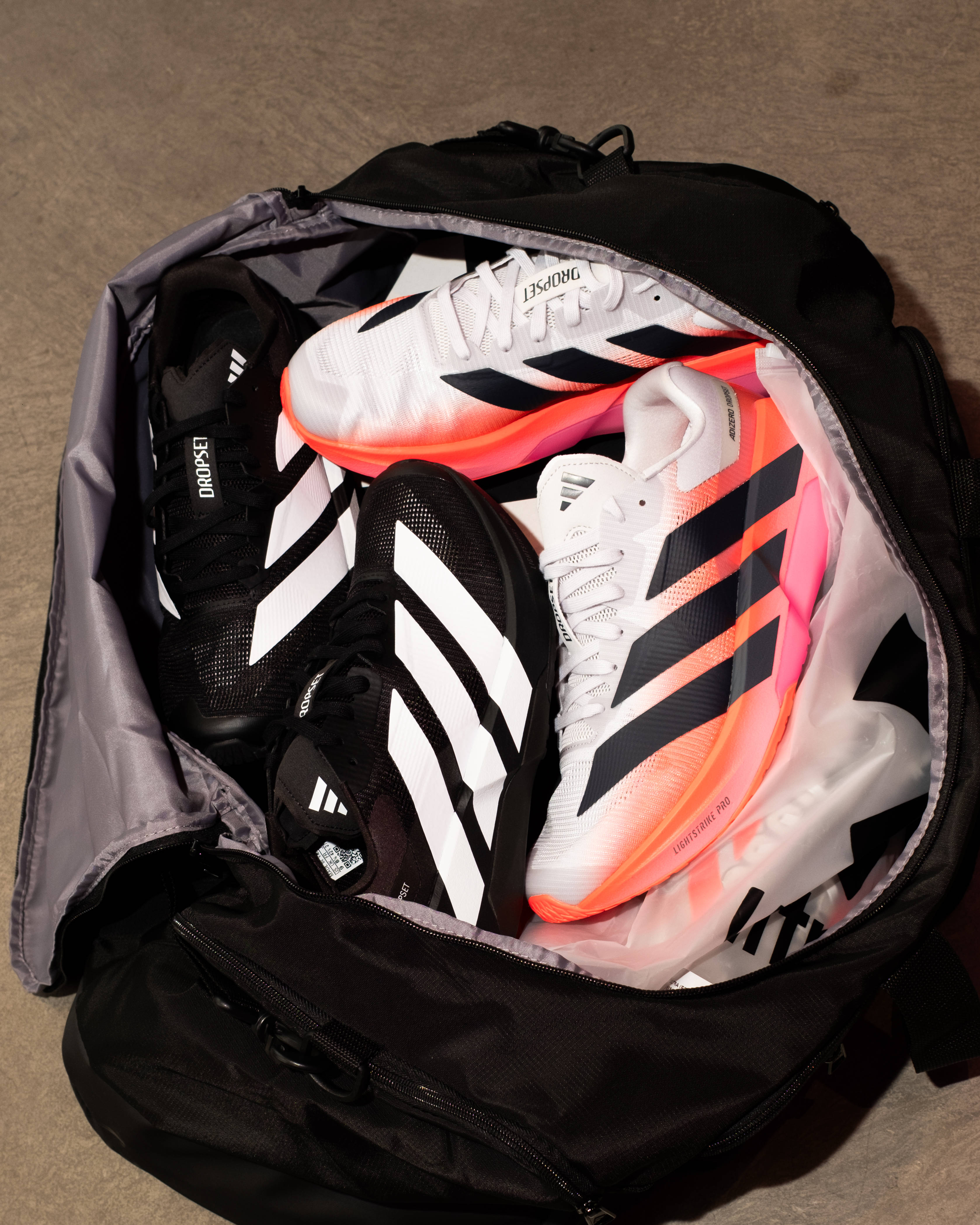adidas adizero dropset pro black white and white pink colourway in duffle bag top down shot