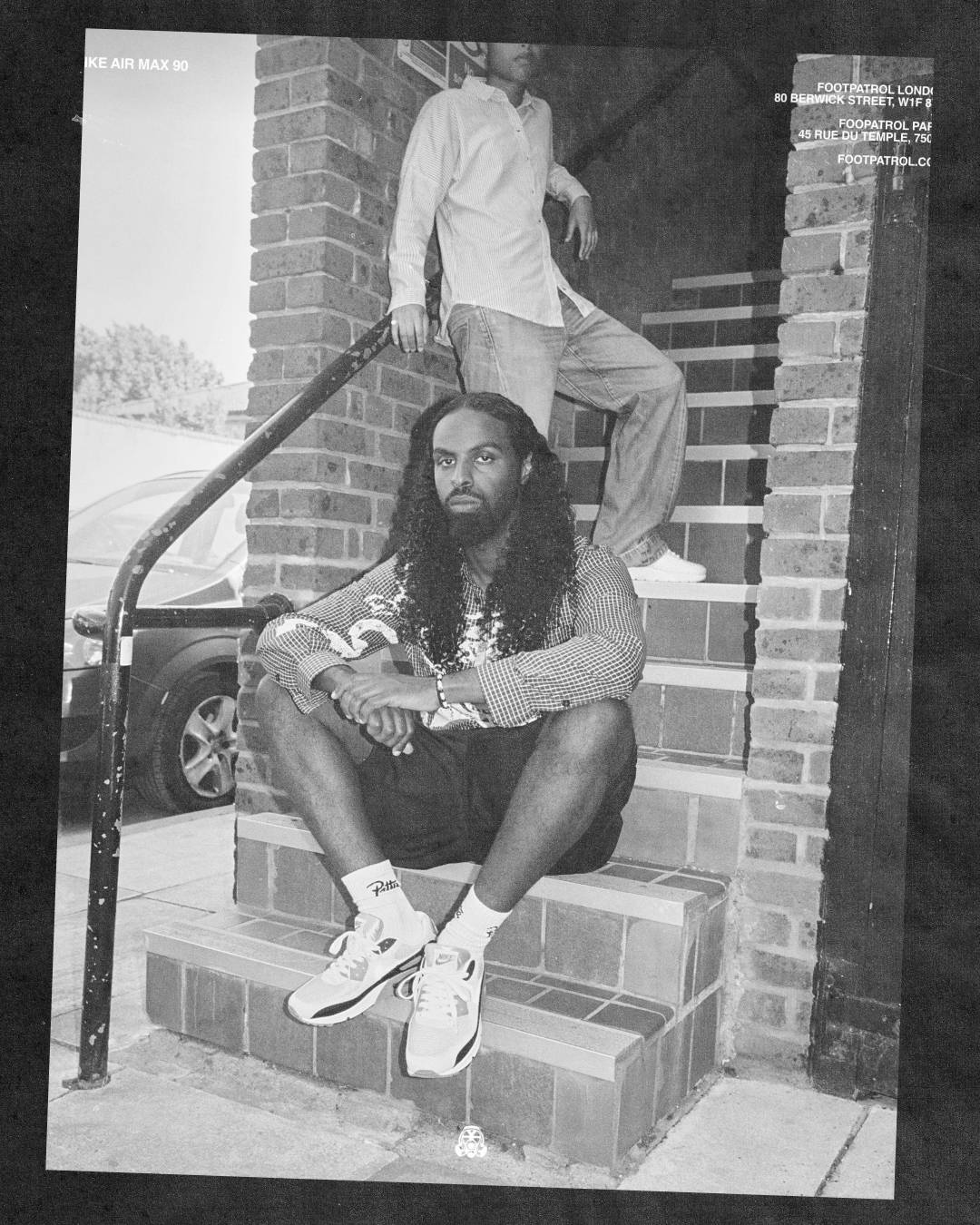 long haired male model seated pose wearing Nike air max 90s black and white image