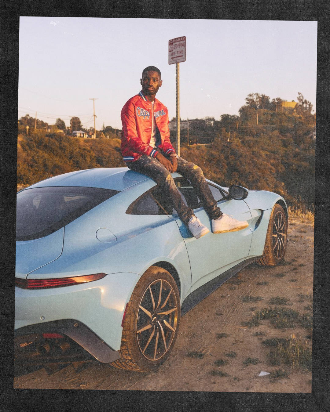 Dave sat on supercar wearing Air Force 1 white on white as the sun sets