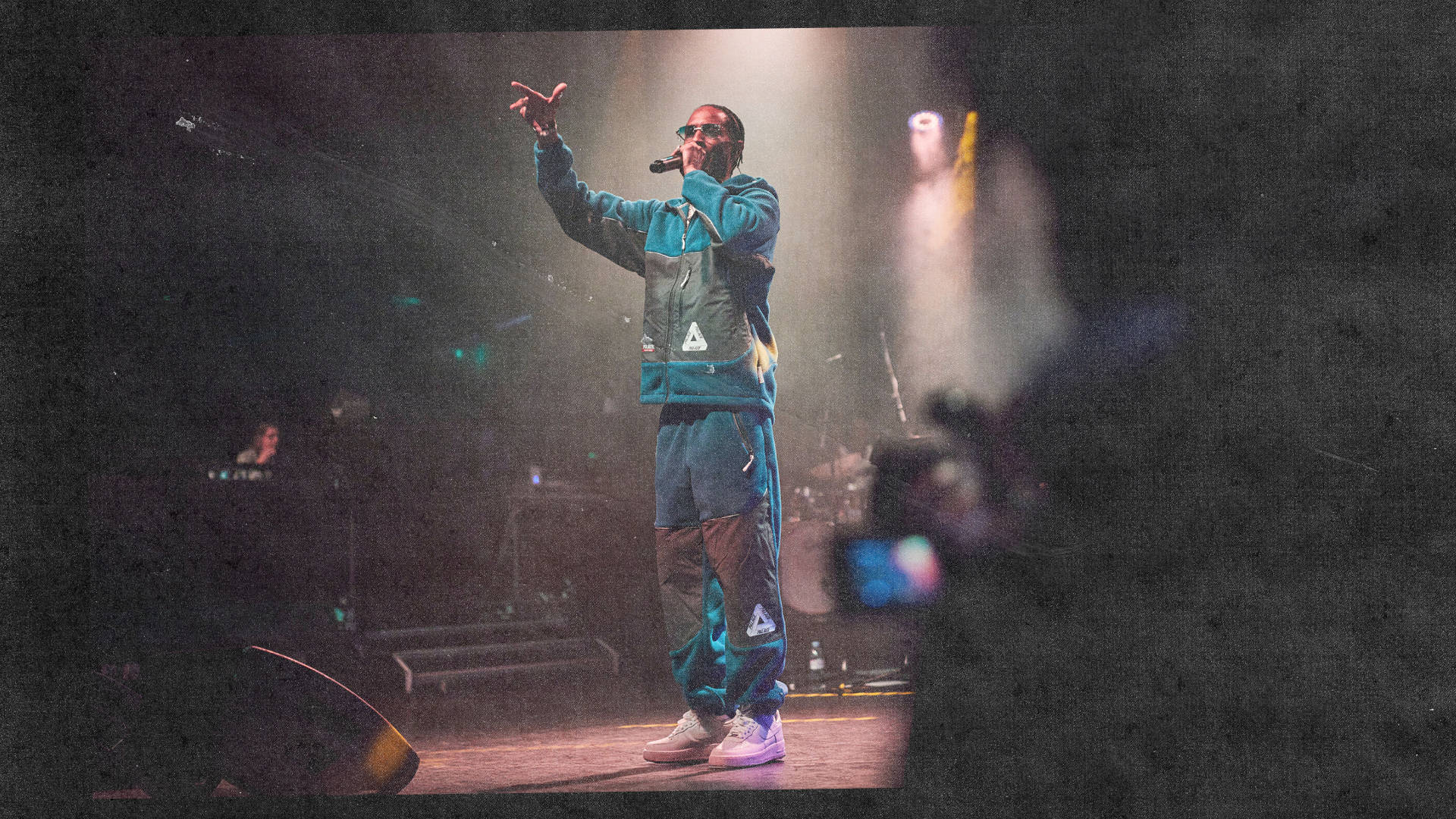 d double e grime mc performing on stage in Palace polartech tracksuit and triple white air force 1s